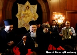 Вселенський патріарх Варфоломій із пакетами цукерок фабрики «Рошен». Під час зустрічі з дітьми він пожартував, що від президента Петра Порошенка взяв за автокефалію для церкви України не гроші, а цукерки і шоколад. Він пояснив, що Порошенко має шоколадну фабрику і, як і президент США Дональд Трамп, є підприємцем. «Хоча російська церква звинувачує мене в тому, що я взяв гроші за цю автокефалію, я взяв не гроші, а багато цукерок і шоколаду з фабрики Порошенка», – сказав патріарх Варфоломій. Після цього він роздав цукерки дітям, які прийшли колядувати в резиденцію патріарха. Стамбул, 24 грудня 2018 року