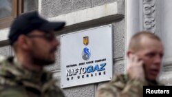Bărbați în trecere pe lângă sediul companiei Naftogaz din Kiev, Ucraina. Imagine din arhivă
