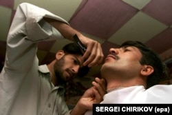 A barber shaves a customer who decided to get rid of his beard -- something forbidden under the Taliban regime -- in the Afghan town of Taloqan in November 2001.