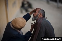 A roadside barber trims a customer's beard at a street shop in Kabul in 2010.