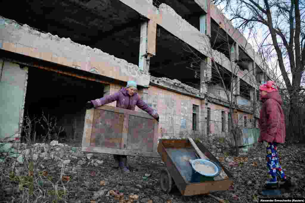 Angelica, 49-vjeçare, dhe e bija e saj, Anastasiya, 13-vjeçare, duke mbledhur pjesë mobiliesh, për t'i djegur për ngrohje, pranë një ndërtese të braktisur të një miniere qymyri, në qytetin e Horlivkës, që kontrollohet nga rebelët, pranë Donetskut, në Ukrainë. (24 nëntor)