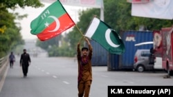 یکی از طرفداران عمران خان از حزب تخریک انصاف بیرق این حزب را یکجا با بیرق پاکستان روی یکی از جاده ها حمل میکند 