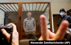 Navalnîi într-o cușcă în tribunalul din Moscova, pe 20 februarie 2021. Decizia sa de a se confrunta direct cu guvernul lui Putin cu prețul propriei sale libertăți a devenit pentru mulți un exemplu definitoriu și dătător de inspirație.