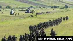 Іспанські, німецькі та голландські солдати біля військових гелікоптерів німецької, іспанської та румунської армій на полігоні в Румунії, 14 травня 2024 року