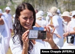 A White Brotherhood member with a cell phone featuring a portrait of Peter Deunov.