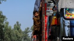 یو افغان هلک په داسې حال کې چې کورنۍ یې کور ته ستنیږي له سامانونو ډکه لارۍ څخه ښکته کېږي ـ د نومبر دریمې انځور.