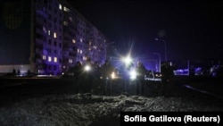 Люди стоять біля кратера, що з'явився після удару російського безпілотника в Харкові, Україна, 30 січня 2024 року