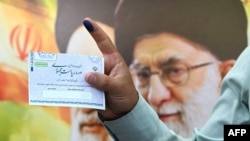 A man holds up a ballot during the first round of Iran's presidential election on June 28.