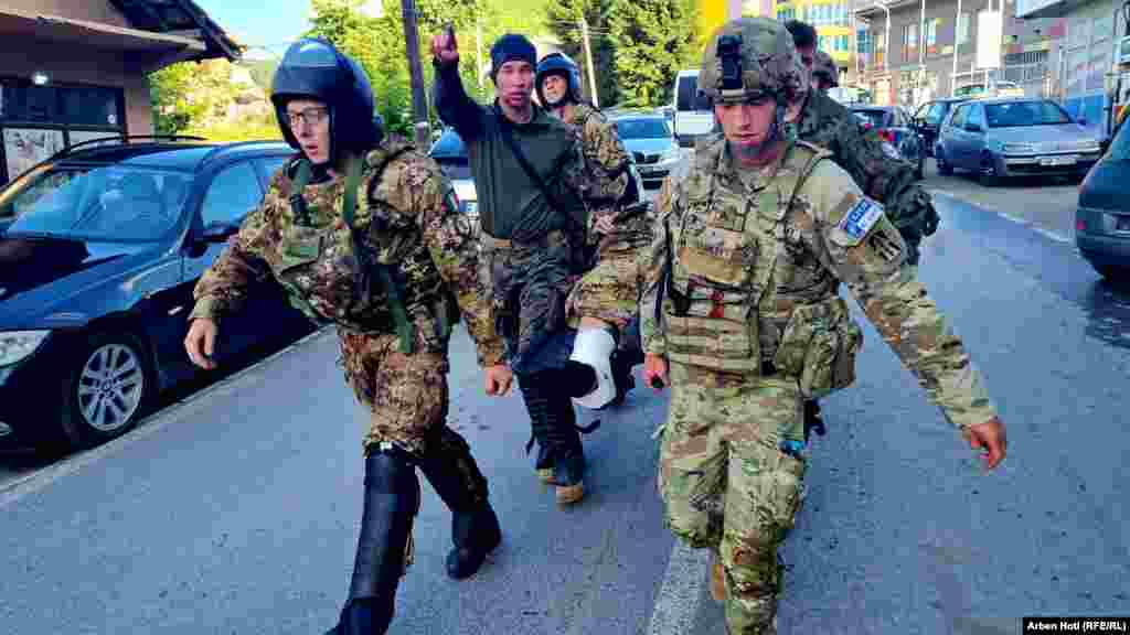 Pjesëtarë të KFOR-it duke bartur një ushtar të lënduar. Misioni paqeruajtës i NATO-s, KFOR, ndërhyri për t'i shpërndarë protestuesit në Zveçan. Paraprakisht i paralajmëroi protestuesit që të shpërndahen, por ata nuk u bindën. &nbsp; 