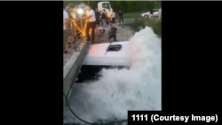 Каналга түшүп, көпүрөнүн астына тыгылып калган кичи автобус. Видеодон алынган скриншот.