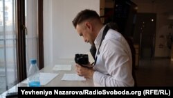 Сергій Звілінський фотографує родинні документи, які вимушені переселенці принесли на захід очолюваного ним історичного товариства