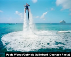 Un angajat al Jetpack Cayman face o demonstrație de sport nautic în apele de lângă coasta Insulelor Cayman. Mike Thalasinos, proprietarul companiei, observă: „Jetpack-ul oferă senzația de gravitație zero. În plus, Insulele Cayman au zero taxe. Ne aflăm în locul potrivit!”