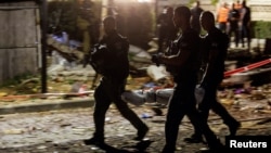 MIlitari israeliani transportă un fragment al unei rachete trase din Gaza aterizată lângă o casă din Ashkelon, Israel.