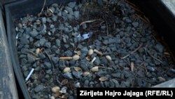 Mbetje cigaresh dhe fëstëkësh të hedhura në një vazo.