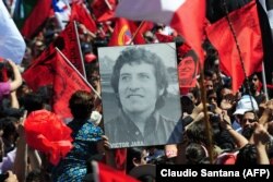 شهروندان سانتیاگو تصاویری از خارا را در زمان دفن مجدد او در سال ۲۰۰۹ بر دست دارند