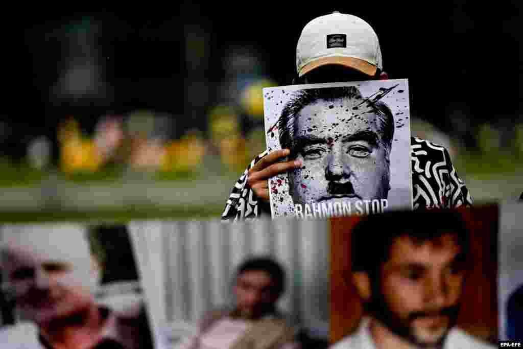 Мужчина держит фотографию с надписью &laquo;Рахмон, остановись&raquo; перед офисом Олафа Шольца во время встречи пяти лидеров Центральной Азии с канцлером Германии. 29 октября 2023 г. (EPA-EFE/Filip Singer)