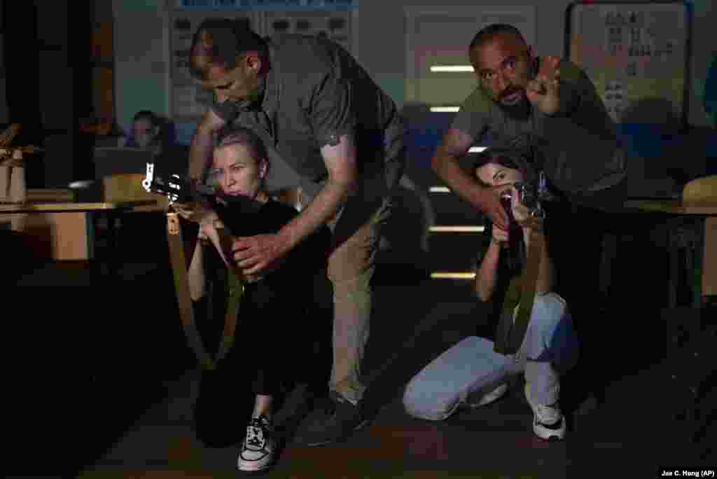 Două femei cu pistoale-mitralieră AK-47 de exercițiu învață cum să tragă în timpul unui curs de pregătire la Kiev, la 11 iulie. Autoritățile din capitala țării oferă civililor antrenamente de supraviețuire, inclusiv cum să tragă cu arma, să acorde primul ajutor și să recunoască minele terestre.