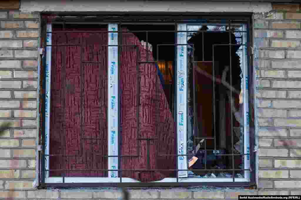 Чоловік завішує вибите вікно