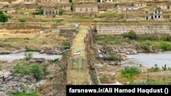 The Iranian and Azerbaijani flags fly on opposite ends of the Khodafarin Bridge on the border of the two countries.