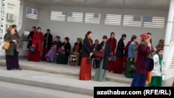 Jemgyýetçilik transport duralgasyndaky aýallar. Aşgabat, 2024-nji ýylyň marty.