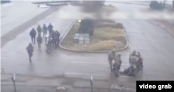 ҰҚК қызметкерлерінің "Жабайы Арман" тобы ұстап берген адамдарды контейнерге ұрып, теуіп тасып жатқан сәті. Алматы әуежайы, 7 қаңтар, 2022 жыл