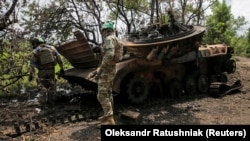 Украинские военнослужащие осматривают уничтоженную российскую БМП-2 в селе Сторожевое Донецкой области, освобожденном от российской армии, 14 июня 2023 года