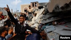 فلسطینیان په خان یونس کې تر اسراییلۍ بمبارۍ وروسته له ړنګې ودانۍ څخه د وژل شویو او ژوبلو د ایستلو چارې پر مخ وړي - د اکتوبر اتمې انځور.