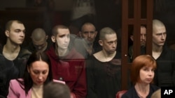 На задньому плані (за склом) ув’язнені українські громадяни в суді у російському Ростові-на-Дону, більшість із них – військовополонені, бійці полку «Азов»,14 червня 2023 року