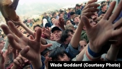 Refugjatë shqiptarë nga Kosova, të dëbuar nga shtëpitë e tyre nga forcat serbe, duke marrë bukë nga pjesa e pasme e një kamioni, në një rrugë në qytetin e Kukësit, në Shqipëri.