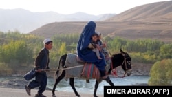 Një grua e mbuluar me burka dhe fëmijët e saj, duke udhëtuar me një gomar, në provincën afgane Badakshan. Tetor 2023.