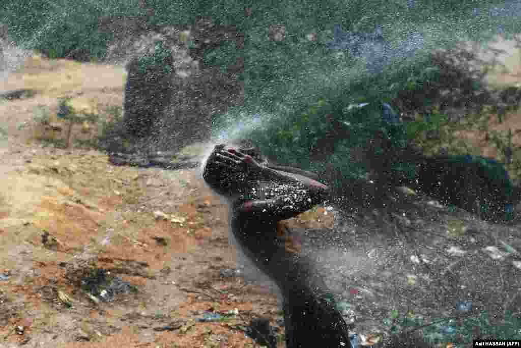Căldură mare. Un bărbat se răcorește într-un pârâu din Karachi, Pakistan.