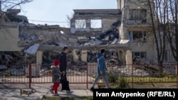 Residents of Ukraine's Kherson city walk past the building of the Kherson Academy of Continuing Education, which was destroyed by Russian attack UAVs. March 2024