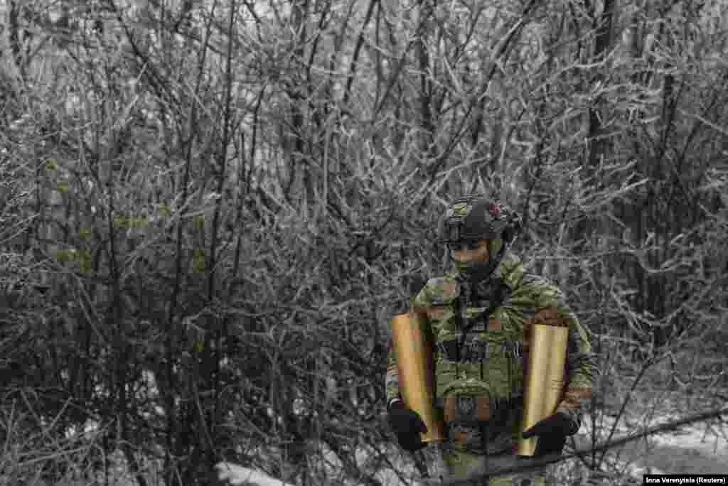 A soldier carries shells to a self-propelled howitzer. &nbsp;