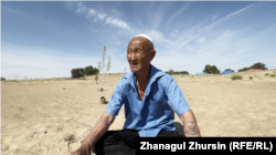 Uais Akhmetov sits near saplings that the villagers hope will impede the progress of the sand that is invading their homes and destroying their community.