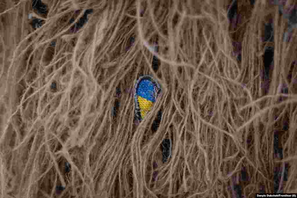 Маленька нашивка з українським прапором, захована всередині кікімори. Катерина служить в українській армії вже понад п'ять років, проте не планує залишатися у війську після перемоги України. &laquo;Я хочу подорожувати по світу, хотіла б ще раз поїхати в Іспанію, Фінляндію, Америку&raquo;, &ndash; каже вона. Найважче, за її словами, визнати той факт, що війна, яку розпочала Росія, навряд чи закінчиться найближчим часом. &laquo;Ти робиш великий вклад у це і ти не розумієш, де межа, і чи ти взагалі доживеш до цієї межі&raquo;, &ndash; каже вона. Ця фотогалерея є адаптованою версією репортажу Олени Максименко та Данило Дубчака, яку вперше опублікував Frontlineer