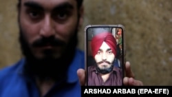 Harmindar Sikh shows the photo of his brother Manmohan Singh, reportedly killed by IS-K militants in Peshawar on June 25.