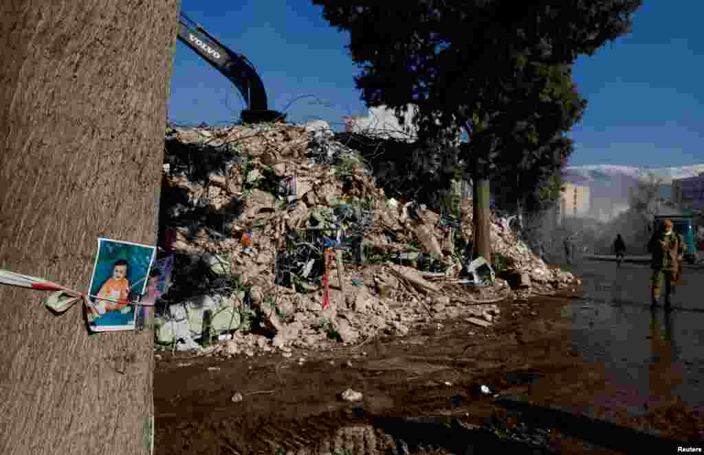 Қаһраманмараш қаласында үйінді жанындағы ағашқа ілінген баланың суреті. 16 ақпан, 2023 жыл.&nbsp; Америкалық JP Morgan қаржылық компаниясы 16 ақпанда "Түркияға жер сілкінісінен келген шығын 25 млрд долларға дейін жетуі мүмкін" деп мәлімдеді.