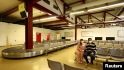 Українська пара, яка тікає від вторгнення Росії в Україну з Мелітополя, у зоні очікування колишнього аеропорту Тегель, який було перетворено на центр розміщення біженців у Берліні, Німеччина, листопад 2022 року