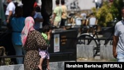 Një grua mban në dorë një fëmijë teksa lyp para në rrugët e Prizrenit, Kosovë.