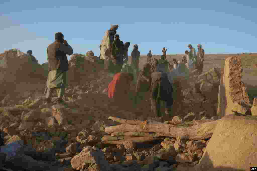 شماری از باشندگان قریه سربلند ولسوالی زنده جان هرات در حال دور کردن آوار یک منزل ویران شده در اثر زلزله روزشنبه در این ولایت اند. آنها تلاش دارند تا افراد گیرمانده و اجساد را از زیر آوار بیرون بکشند