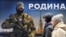 Люди проходят мимо стенда с изображением российского военнослужащего и надписью "Родину, которую мы защищаем" на уличной выставке плакатов на военную тематику в центре Санкт-Петербурга 