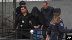 Suspectul în cazul împușcăturilor, cu capul acoperit de o haină, este escortat de poliție în fața școlii primare Vladislav Ribnikar din Belgrad, la 3 mai.