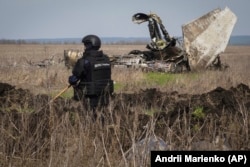A sapper from the Ukrainian State Emergency Service works to demine a site near Izyum, Kharkiv region.