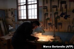 Zatvorenik radi na komadu drveta koji dolazi iz migrantskog čamca kako bi napravio violinu u okviru projekta "Violine mora" u zatvoru, u blizini Milana, 8. februara 2024. ​