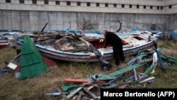 Zatvorenik pregleda migrantski čamac u dvorištu zatvora u blizini Milana, gdje se reciklira drvo ovih čamaca u muzičke instrumente kao dio projekta "Violine mora", februar 2024.