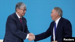 Президент Казахстана Касым-Жомарт Токаев пожимает руку бывшему президенту Нурсултану Назарбаеву на съезде правящей партии «Нур Отан» в Нур-Султане. Казахстан, 23 апреля 2019 года