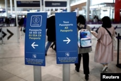 Semnele indicatoare pentru controlul pașapoartelor sunt vizibile într-un aeroport din Paris.