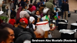 Рафахта кайрымдуулук уюмдары тараткан тамакка кезекке турган качкындар. 13-февраль, 2024-жыл.