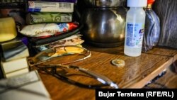 Një monedhë prej 2 eurosh shihet në një komodinë me disa gjësende personale. Për shtëpinë ku jeton, Sakibe Jashari, paguan 75 euro qira.