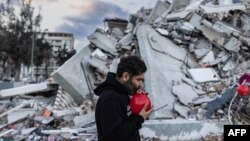 38 ýaşly türk Ogun Sewer Okur, Türkiýäniň günortasynda bolan weýrançylykly ýer titremesinde ölen çagalaryň hatyrasyna Antakýadaky ýykylan binanyň harabalygynda gyzyl şarlary ýerleşdirýär.